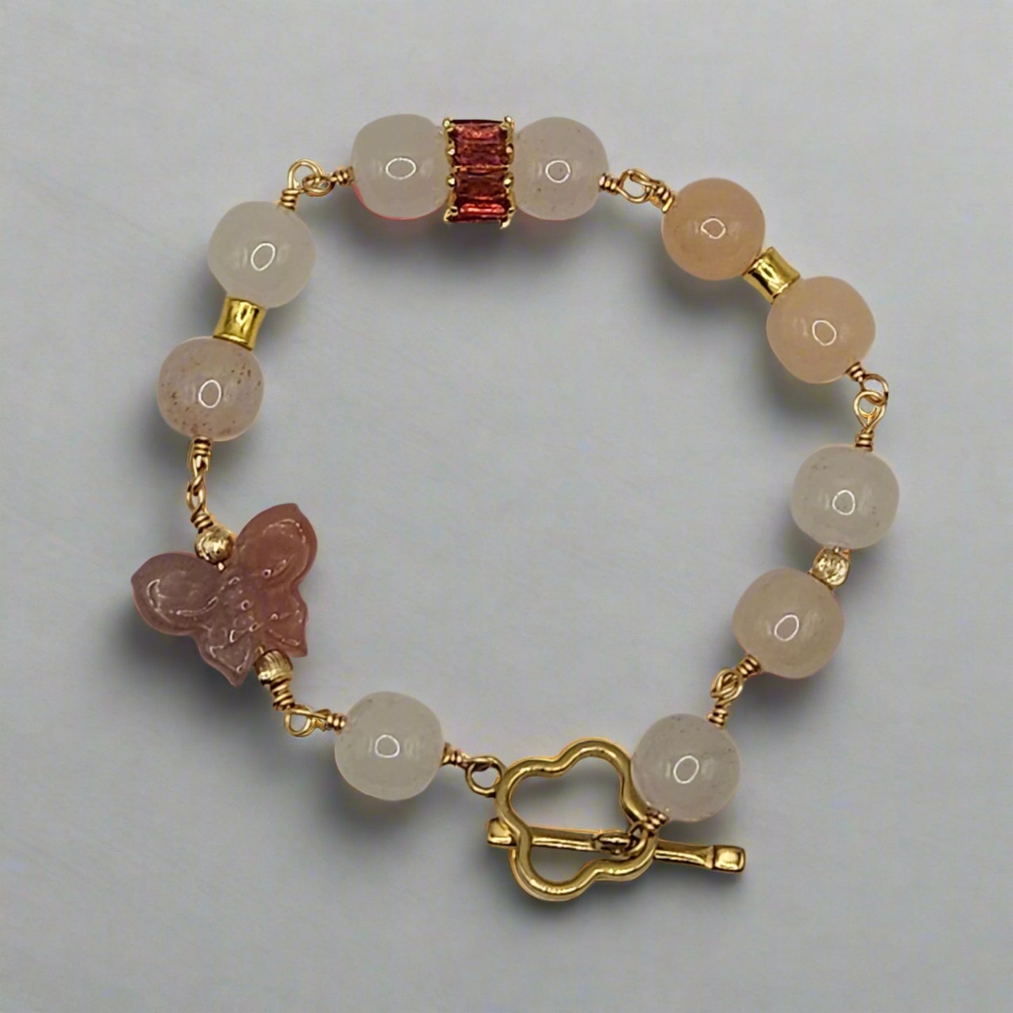 Bracelet with natural stone beads and gold accents on a light gray background