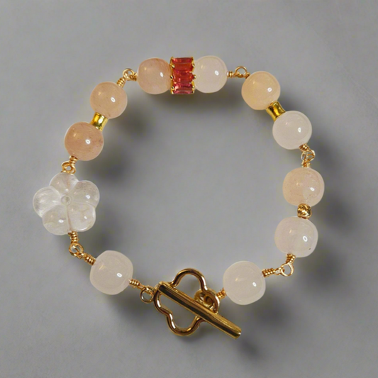 A bracelet with round golden silk jade and clear quartz beads, featuring a gold-colored clasp and gold plating.