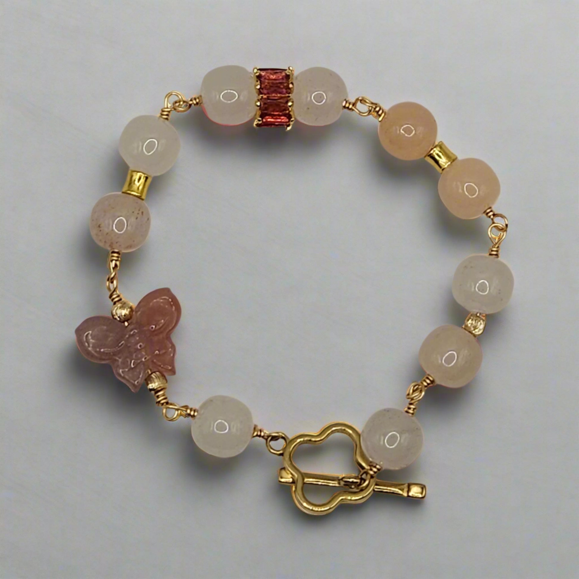 Bracelet with natural stone beads and gold accents on a light gray background